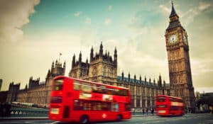 The Best Pub Guide - Two iconic red double-decker buses glide past the majestic Houses of Parliament and the ever-watchful Big Ben in London, all under a quintessentially cloudy sky. It’s a classic Greater London scene—perfect inspiration for discovering local gems, exploring top UK pub listings, or finding the best dog-friendly pubs for your next adventure. | Pub Directory UK