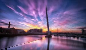 The Best Pub Guide - Swansea’s modern cable-stayed bridge stretches gracefully over tranquil waters, setting the scene beneath a sunset sky streaked with vibrant pinks and purples. As you wander along the waterfront, you’ll spot boats bobbing beside gleaming buildings—all perfectly reflected for that just-right evening atmosphere. It’s an ideal stroll before popping into nearby pubs for a pint or searching out one of Swansea’s dog-friendly haunts. | Pub Directory UK